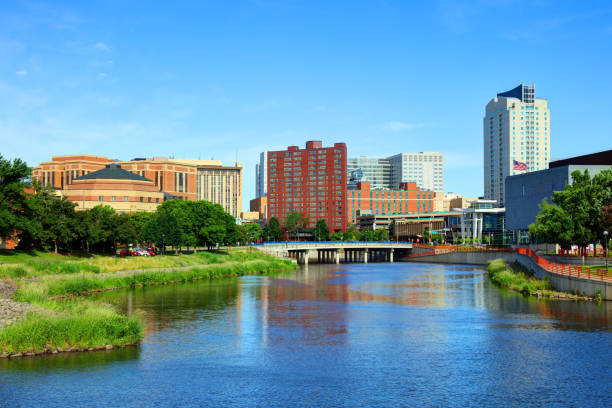 A bright, blue sky day looking out over the blue waters and lush green banks of the winding Zumbro River with the Rochester city skyline in the background.
